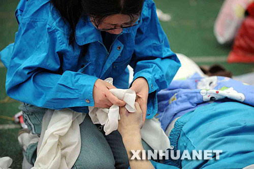 5月14日，張關蓉在擦拭丈夫譚千秋的遺體。 受汶川地震影響，四川省德陽市東汽中學教學樓坍塌。在地震發(fā)生的一瞬間，該校教導主任譚千秋雙臂張開趴在課桌上，身下死死地護著4個學生，4個學生都獲救了，譚老師卻不幸遇難。 新華社記者王建華攝