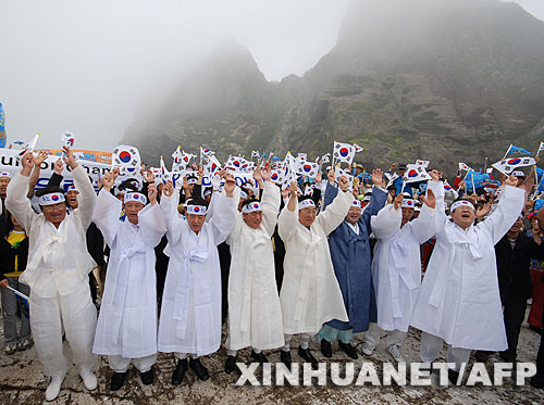  7月14日，大批韓國人在獨島（日本稱“竹島”）手舉國旗抗議。韓國外交通商部發(fā)言人文太暎當日發(fā)表聲明，強烈抗議日本在當天公布的中學教科書指導手冊中將獨島（日本稱“竹島”）表述為日本領(lǐng)土，并要求日本立即對有關(guān)內(nèi)容進行修正。韓國外交通商部將采取召回韓國駐日本大使和召見日本駐韓國大使這兩項外交措施，就此問題向日本政府表示強烈抗議。 新華社/法新 