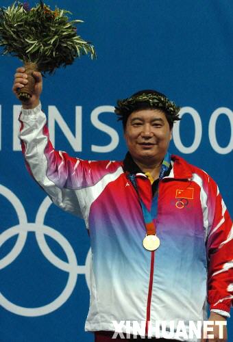 2004年8月14日，王義夫獲第28屆雅典奧運會射擊男子10米氣手槍金牌。圖為王義夫在領(lǐng)獎臺上向觀眾致意。 