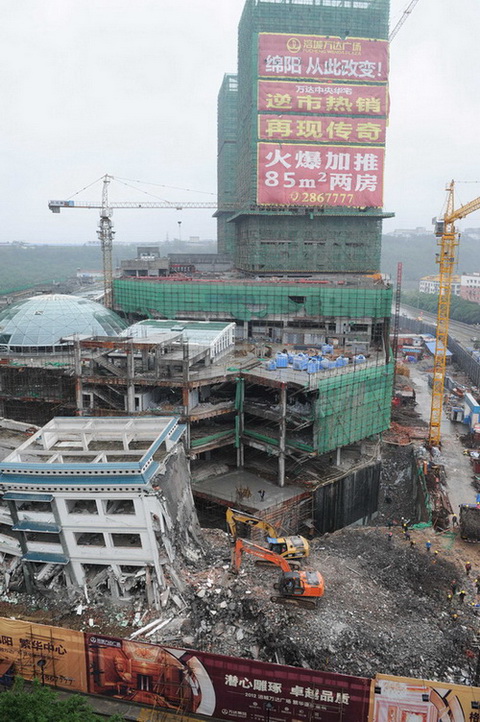 5月21日，工程機(jī)械在拆除綿陽(yáng)紫荊民族中學(xué)校舍，旁邊則是建設(shè)中的萬(wàn)達(dá)廣場(chǎng)。