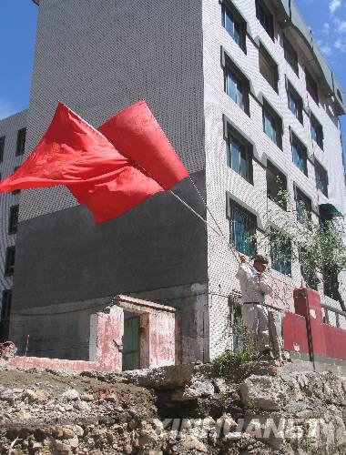  7月5日，一名防化兵高舉紅旗在北川縣城內(nèi)行走。當(dāng)日，記者經(jīng)特許進(jìn)入地震重災(zāi)區(qū)北川縣城采訪，用相機(jī)記錄下北川縣城的現(xiàn)狀。 
